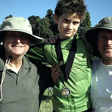 A boy with a medal between his father and grandfather.