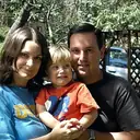 A young family of three in a garden.